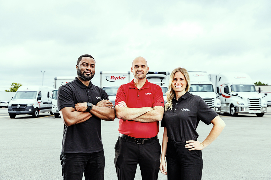 trustworthy transportation workers in front of different types of Ryder freight service vehicles